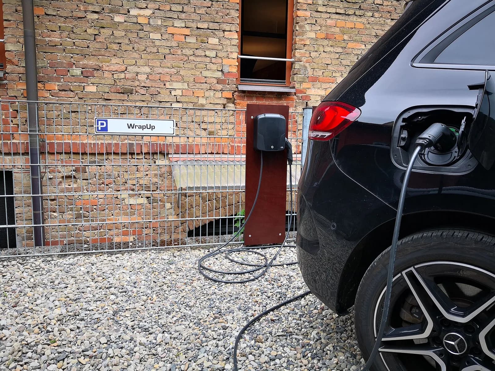 Voiture en charge sur une borne dans une cour pavée