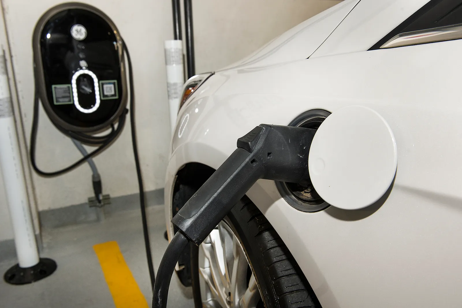 Câble de recharge branché sur une voiture électrique près d'une borne murale