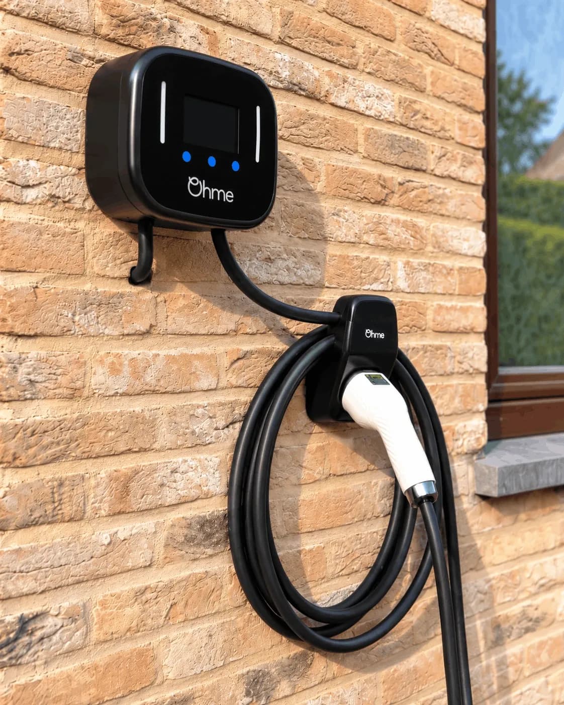 Borne Ohme et support du connecteur fixés au mur extérieur en briques beiges, vue de côté