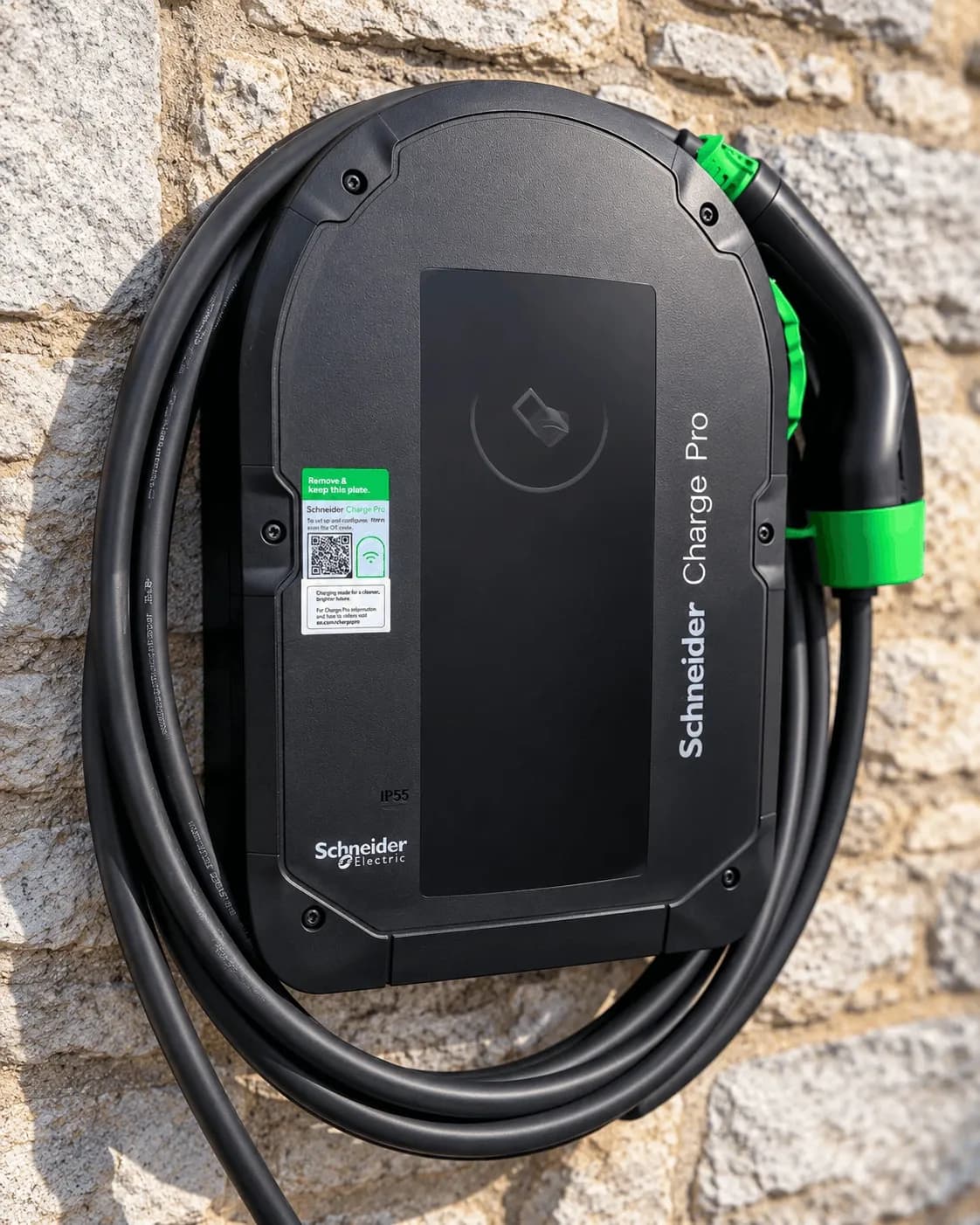 Détail de la borne Schneider Charge Pro et de son câble de recharge sur le mur en pierre